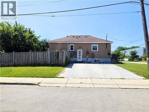 Rear exterior featuring a privacy fence, paved driveway, and established landscaping - 353 East 21St Street, Hamilton, ON - Outdoor
