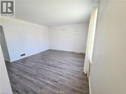 Spacious room featuring wood-finish flooring, white walls, and a window for natural light - 353 East 21St Street, Hamilton, ON - Indoor Photo Showing Other Room