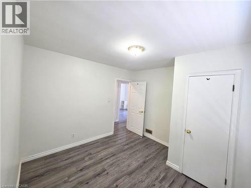Spacious bedroom with wood-finish flooring, white painted walls, and abundant natural light from recessed ceiling fixture - 353 East 21St Street, Hamilton, ON - Indoor Photo Showing Other Room