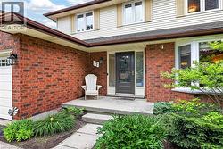 Brick and siding exterior featuring a covered front entry with a dark-framed glass door, a bay window, and exterior lighting fixtures - 