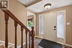 Entryway featuring a paneled door with frosted sidelights, a coordinated overhead light fixture, wood-finish flooring, and a wooden staircase with balusters - 