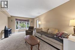 Spacious living area featuring neutral-toned walls, textured carpet flooring, and a large bay window with a garden outlook - 