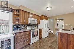 Kitchen featuring wood-finish cabinetry, speckled countertops, and a mosaic tile backsplash - 