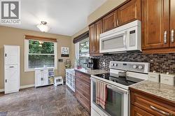Well-appointed kitchen featuring wood cabinetry, stone-look countertops, and a full suite of white appliances - 