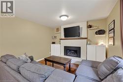 Living area featuring a white brick fireplace with a wood mantle, built-in black firebox, and recessed lighting - 