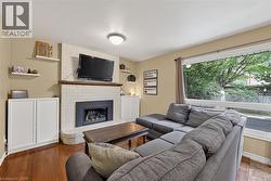 Living area featuring wood-finish flooring, a white brick fireplace with a dark metal insert, and a wood mantel - 