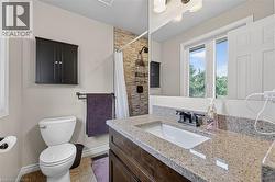 Bathroom featuring a vanity with a light-toned stone-finish countertop, an integrated sink, and a dark-finish faucet - 