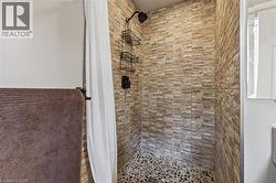 Shower enclosure featuring stacked stone-look wall tile and a pebble floor - 