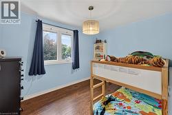 Bedroom featuring wood-finish flooring, a window with exterior views, and a ceiling-mounted light fixture - 