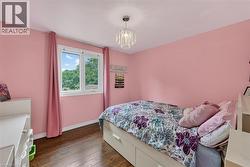 Room featuring hardwood-style flooring, white trim, and a prominent window with white framing - 