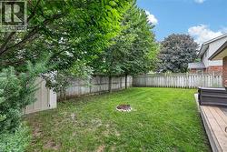 Expansive backyard featuring a lush lawn, privacy fencing, mature trees, a storage shed, and a wood-finish deck - 