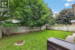Spacious backyard featuring a manicured lawn, established perimeter trees, and a wooden privacy fence - 