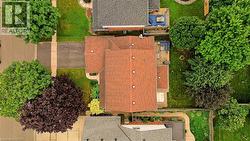 Property featuring a reddish-brown shingled roof, a paved driveway, and established landscaping - 