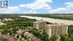 Aerial perspective showcasing two multi-story residential buildings with balconies, surrounded by mature trees - 