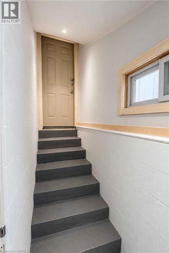 Recessed ceiling light, white painted block walls, wooden door frame, light wood window trim, and dark gray painted stairs - 561 Wentworth Street N, Hamilton, ON - Indoor Photo Showing Other Room