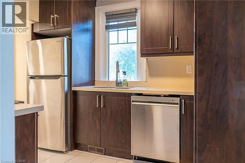 Stainless steel refrigerator, stainless steel dishwasher, wood-finish cabinetry, light-toned countertops, and a window with blinds - 41 Paradise Road S, Hamilton, ON - Indoor Photo Showing Kitchen