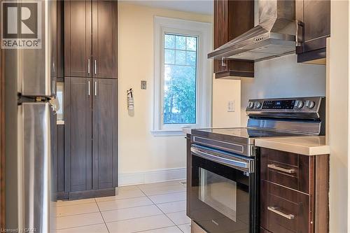 Stainless steel range with coordinating range hood, dark wood-finish cabinetry, light-toned countertop, and tiled flooring - 41 Paradise Road S, Hamilton, ON - Indoor Photo Showing Kitchen