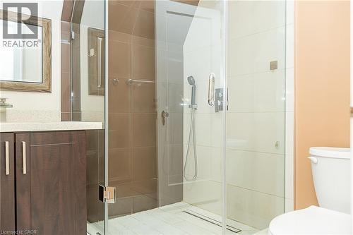Glass-enclosed shower with a handheld shower fixture, wood-finish vanity with a light-toned countertop, and a framed mirror - 41 Paradise Road S, Hamilton, ON - Indoor Photo Showing Bathroom