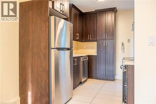 Stainless steel refrigerator, dark wood-finish cabinetry, light tile flooring, light-toned countertops, and a stainless steel dishwasher - 41 Paradise Road S, Hamilton, ON - Indoor Photo Showing Kitchen