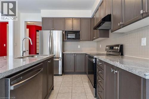 Kitchen featuring light tile patterned floors, under cabinet range hood, stainless steel appliances, a sink, and decorative backsplash - 13 Steven Drive, Thorold, ON - Indoor Photo Showing Kitchen With Double Sink With Upgraded Kitchen