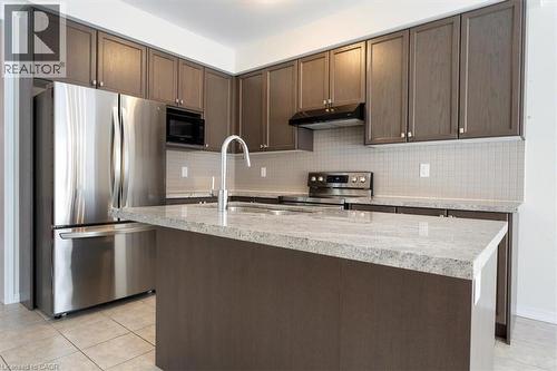 Kitchen featuring under cabinet range hood, tasteful backsplash, light tile patterned floors, and stainless steel appliances - 13 Steven Drive, Thorold, ON - Indoor Photo Showing Kitchen With Upgraded Kitchen