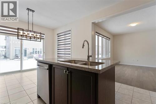 Kitchen featuring light tile patterned floors, stone countertops, dishwasher, open floor plan, and a sink - 13 Steven Drive, Thorold, ON - Indoor Photo Showing Kitchen With Double Sink