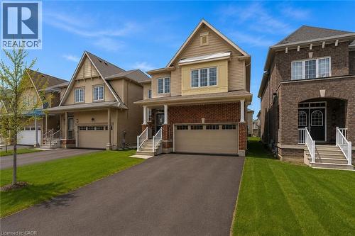 Two-story residence featuring a brick and siding exterior, covered front porch, an attached garage, paved driveway, and manicured front lawn - 13 Steven Drive, Thorold, ON - Outdoor With Facade
