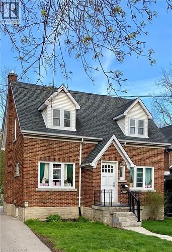 Brick exterior with white trim, featuring a gabled entry porch, dark shingle roof, and two dormer windows - 49 West Avenue, Kitchener, ON - Outdoor