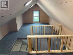 Loft space featuring sloped ceilings, a window, track lighting, and wood railings - 