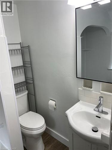 White ceramic toilet with wood-finish flooring - 49 West Avenue, Kitchener, ON - Indoor Photo Showing Bathroom