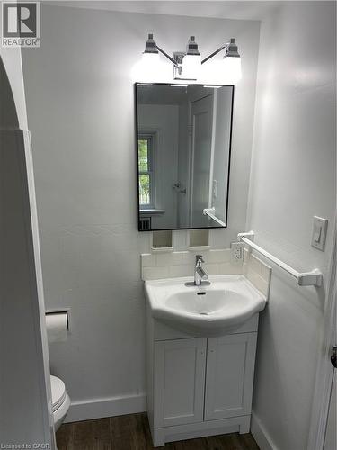 Vanity with integrated sink, chrome faucet, white subway tile backsplash, framed mirror, and chrome-finish lighting fixture - 49 West Avenue, Kitchener, ON - Indoor Photo Showing Bathroom