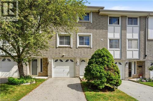 Brick facade with white window trim and white garage doors featuring decorative arched windows - 145 Rice Avenue Unit# 2, Hamilton, ON - Outdoor With Facade