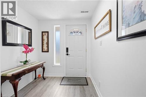 Entryway featuring a solid white door with arched glass detail, a frosted sidelight, light wood-finish flooring, and white wall finishes - 145 Rice Avenue Unit# 2, Hamilton, ON - Indoor Photo Showing Other Room