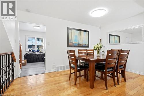 Hardwood flooring, white walls, flush mount ceiling light, wrought iron stair railing, and a window with horizontal blinds - 145 Rice Avenue Unit# 2, Hamilton, ON - Indoor Photo Showing Dining Room