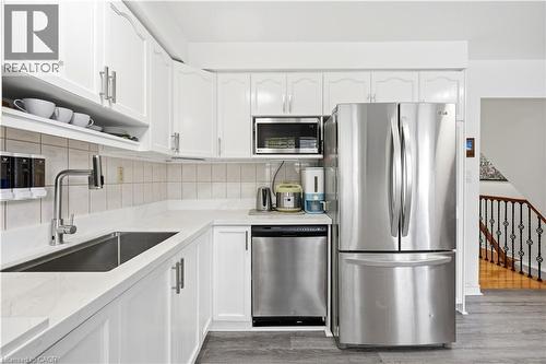 Kitchen featuring white cabinetry, light countertops, stainless steel appliances, and wood-finish flooring - 145 Rice Avenue Unit# 2, Hamilton, ON - Indoor Photo Showing Kitchen
