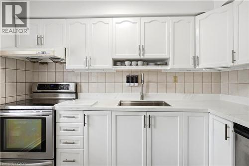 White cabinetry with silver-tone hardware, stainless steel sink, light-toned countertops, and a tiled backsplash - 145 Rice Avenue Unit# 2, Hamilton, ON - Indoor Photo Showing Kitchen