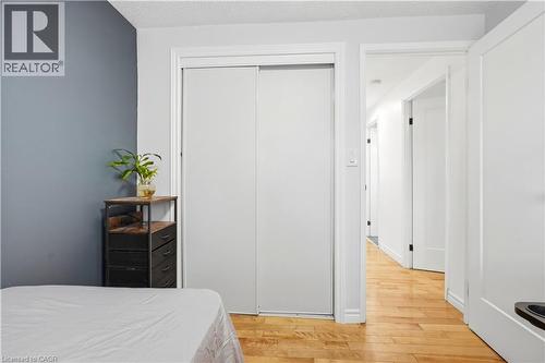 Wood-finish flooring extending into the hallway, white interior doors, and a sliding closet door - 145 Rice Avenue Unit# 2, Hamilton, ON - Indoor Photo Showing Bedroom