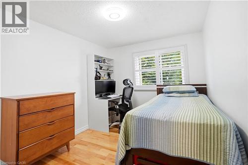 Hardwood flooring, white painted walls, built-in shelving, window with plantation shutters, and a flush mount ceiling light - 145 Rice Avenue Unit# 2, Hamilton, ON - Indoor Photo Showing Bedroom