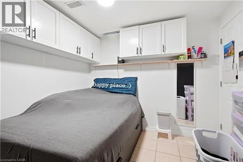 White cabinetry with black hardware, wall-mounted shelving, neutral tile flooring, and white painted walls - 145 Rice Avenue Unit# 2, Hamilton, ON - Indoor Photo Showing Bedroom