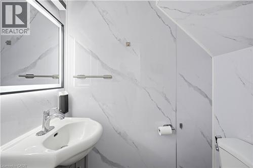 White porcelain sink with chrome faucet, illuminated mirror, and white-veined wall panels - 145 Rice Avenue Unit# 2, Hamilton, ON - Indoor Photo Showing Bathroom