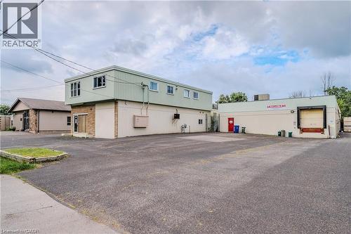 Expansive paved lot with multiple building structures, featuring a single loading dock and a brick facade entrance - 459 Enfield Road, Burlington, ON 