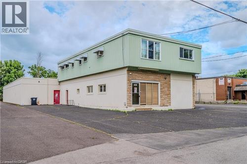 Modern mixed-use commercial structure featuring a distinctive two-story design with sage green upper-level cladding and contrasting cream-colored lower section - 459 Enfield Road, Burlington, ON 