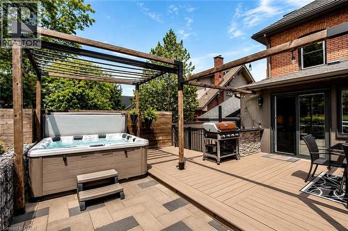 Composite decking with a built-in spa, stone-clad outdoor kitchen, and sliding glass door access - 99 Hillcrest Avenue, Hamilton, ON - Outdoor With Deck Patio Veranda With Exterior