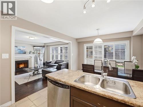 Kitchen peninsula with a double stainless steel sink and speckled countertop - 98 Willow Lane, Grimsby, ON - Indoor Photo Showing Kitchen With Fireplace With Double Sink