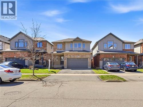 Two-story residence featuring a brick and siding exterior, an attached two-car garage, an asphalt driveway, a covered front entry, and a manicured front lawn - 98 Willow Lane, Grimsby, ON - Outdoor With Facade