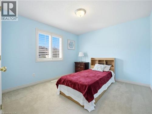 Room featuring light blue walls, light-colored carpeting, a white trim window with plantation shutters, and a flush-mount ceiling light fixture - 98 Willow Lane, Grimsby, ON - Indoor Photo Showing Bedroom