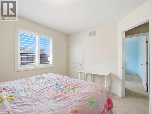 Interior room featuring a window with white louvered shutters, light beige wall paint, and carpeted flooring - 98 Willow Lane, Grimsby, ON - Indoor Photo Showing Bedroom