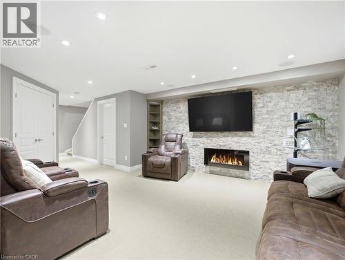 Entertainment room featuring a stone accent wall, linear fireplace, recessed lighting, and built-in shelving - 98 Willow Lane, Grimsby, ON - Indoor Photo Showing Living Room With Fireplace