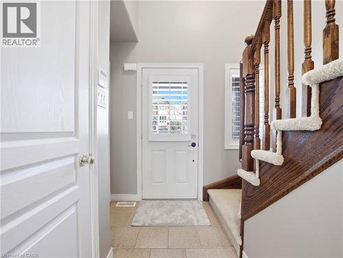 Front entry featuring neutral tile flooring, a white door with louvered glass, and a natural wood staircase with carpeted treads - 98 Willow Lane, Grimsby, ON - Indoor Photo Showing Other Room