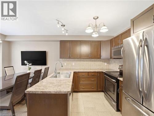 Kitchen featuring wood cabinetry, stainless steel appliances, a double basin sink, and a tile backsplash - 98 Willow Lane, Grimsby, ON - Indoor Photo Showing Kitchen With Stainless Steel Kitchen With Double Sink
